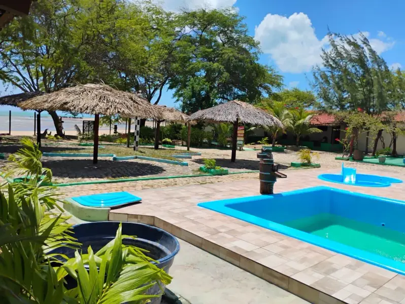 Piscina com quiosques de palha na Pousada do Farol